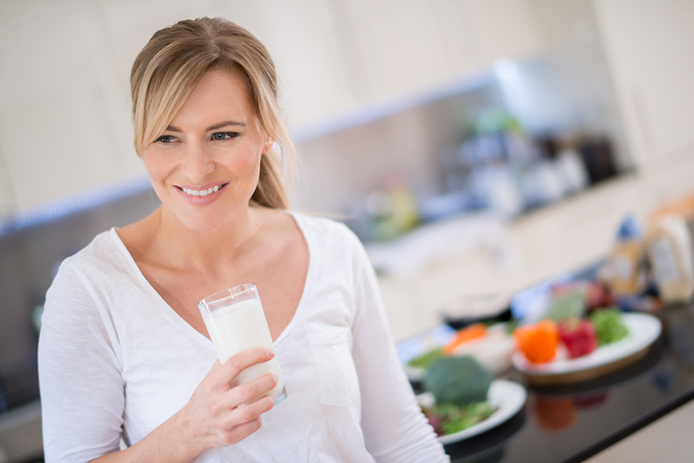 Woman holding a glass of milk and looking happy